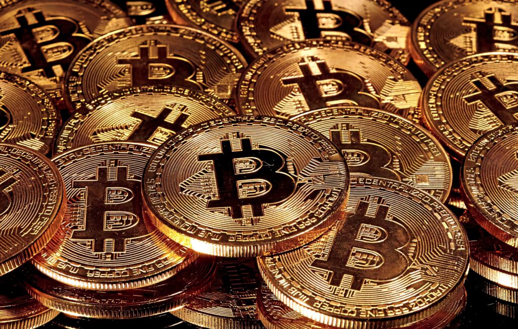 Shiny gold Bitcoin coins piled together vibrant wallpaper representing cryptocurrency finance background