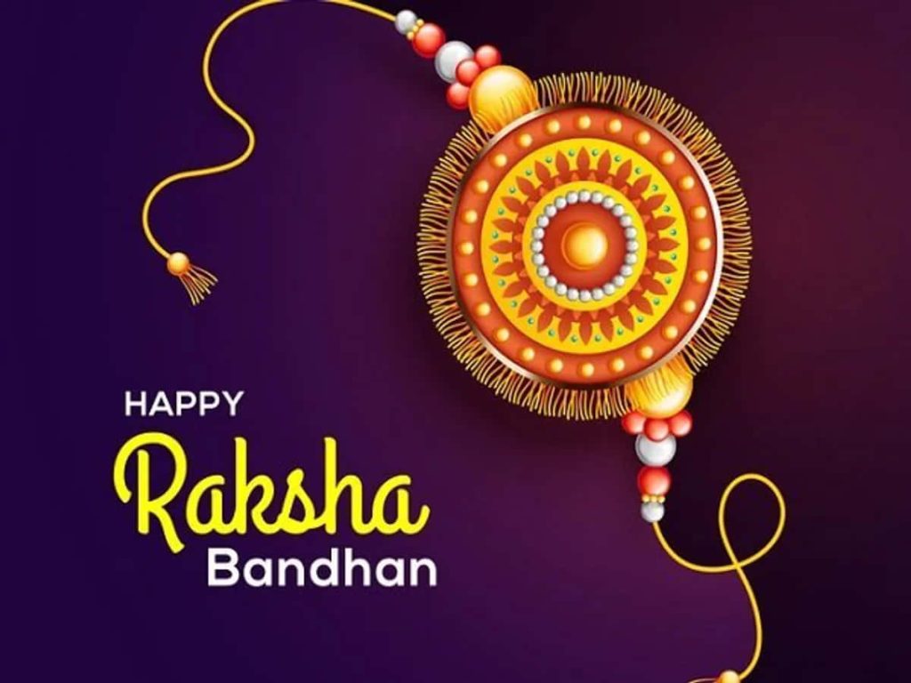 Golden ornate Rakhi on deep purple background with Happy Raksha Bandhan festive greeting wallpaper