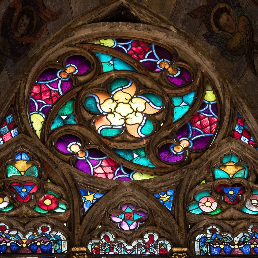 Vibrant Gothic stained glass window with rose pattern angels in red purple yellow church art Wallpaper