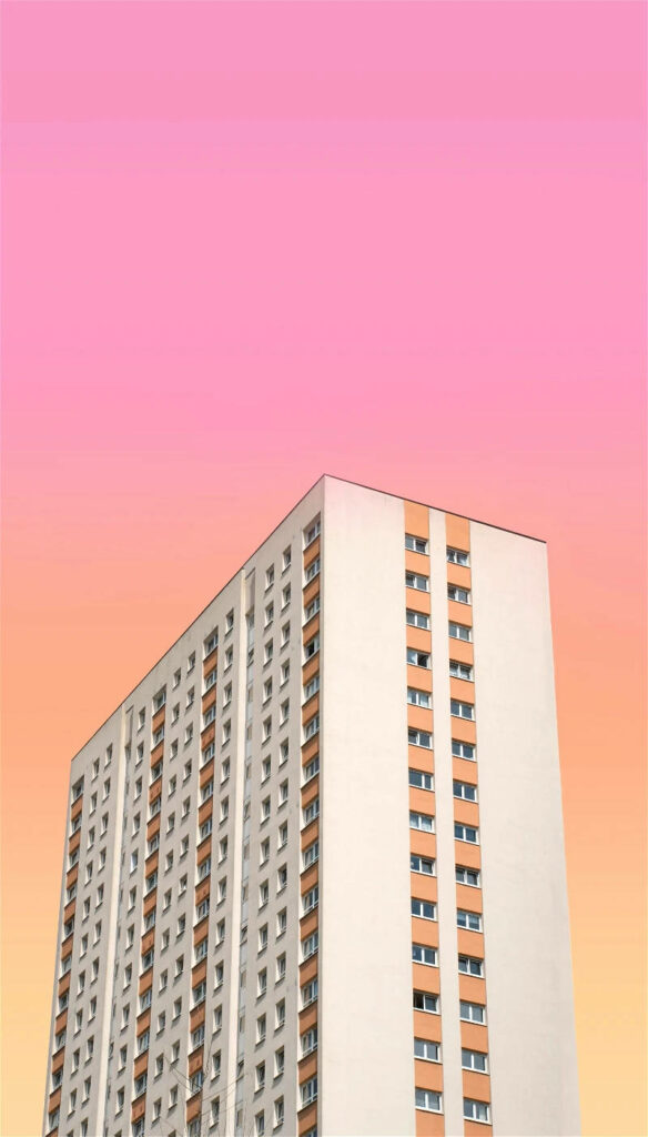 Minimalist Apartment Building against Vibrant Pink-Orange Sky Background Wallpaper