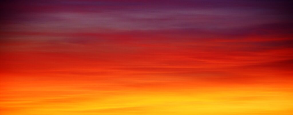 Vibrant sky wallpaper with deep purple red and golden yellow gradient creating warm energy
