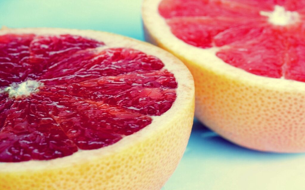 Vibrant Grapefruit Halves Wallpaper: Fresh Citrus on Blue Background