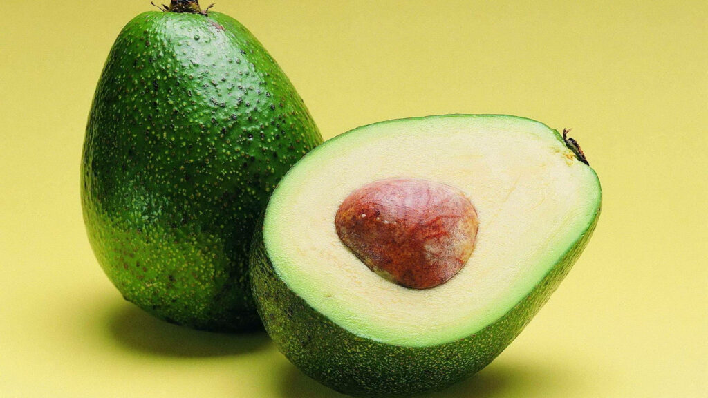 Vibrant Avocado Close-Up Wallpaper on Minimal Yellow Background