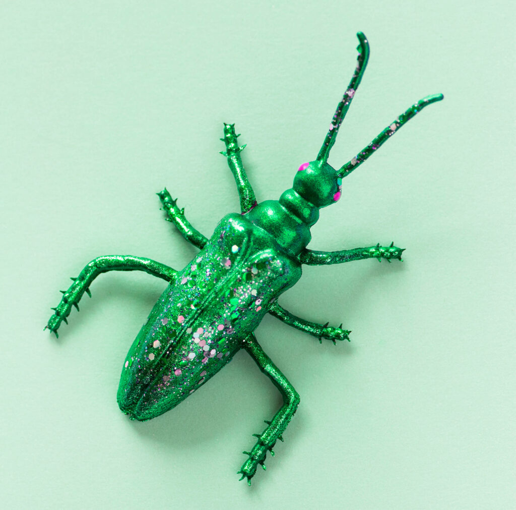 Vibrant Green Beetle Toy Wallpaper with Speckled Nature Background
