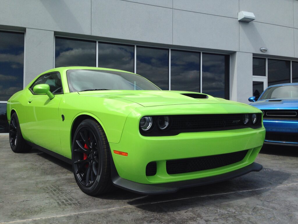 Vibrant Green Dodge Challenger Front View with Modern Architecture Wallpaper