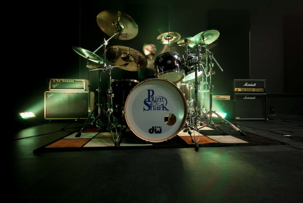Dramatic drum kit in dark studio with vibrant green lights and shiny cymbals wallpaper background