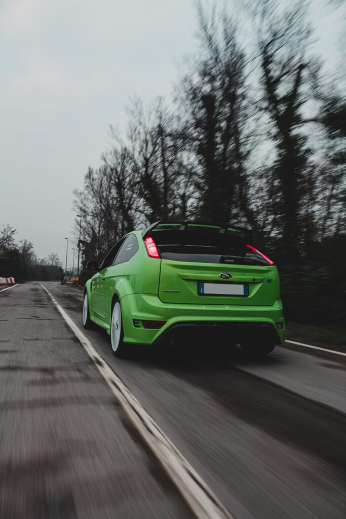 Vibrant Green Ford Focus Racing Down Scenic Open Road Wallpaper