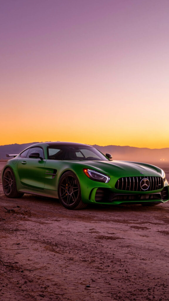 Vibrant green Mercedes-AMG parked on rugged terrain at sunset with glowing warm sky background Wallpaper