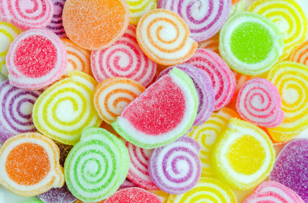 Vibrant gummy candy wallpaper with colorful sugar-coated spirals and fruit-shaped sweets close-up