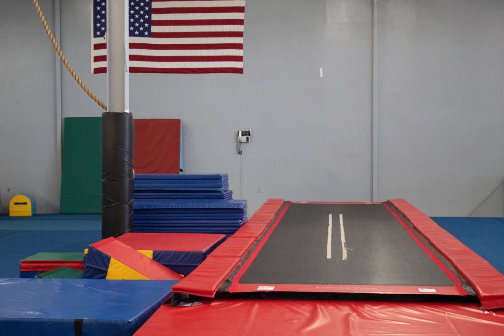 Vibrant professional gymnastics training center with Tumble Trak mats and American flag backdrop Wallpaper