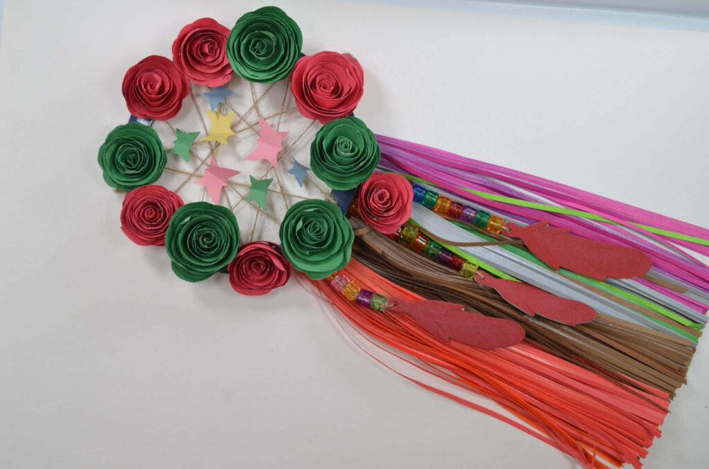Vibrant handmade paper dream catcher with red green roses pastel stars and bright ribbons wallpaper