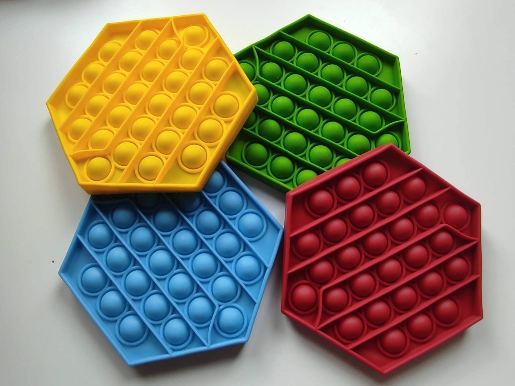 Vibrant wallpaper with four colorful hexagon Pop It fidget toys in yellow green blue red pattern