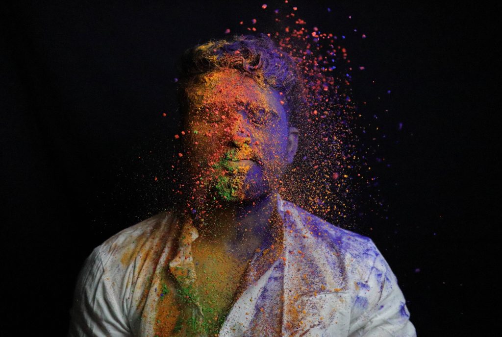 Man celebrating Holi festival with colorful gulal powder burst on white shirt black background Wallpaper