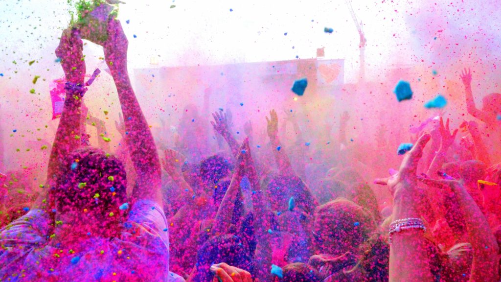 Vibrant Holi festival crowd throwing bright magenta powder in joyful colorful celebration background Wallpaper