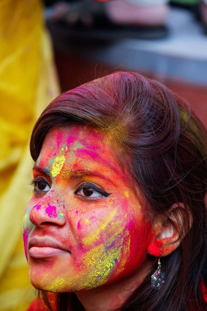 Young woman with colorful gulal powder on face celebrating vibrant Holi festival joyfully Wallpaper