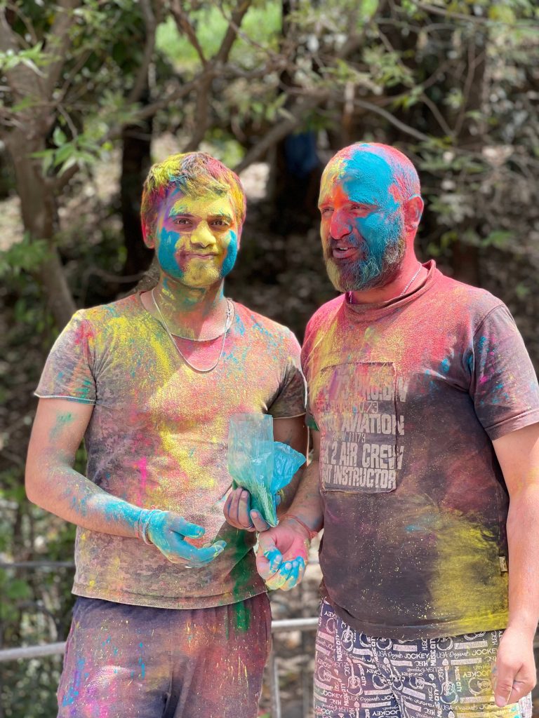 Two men covered in bright Holi colors celebrating the Hindu festival outdoors vibrantly Wallpaper