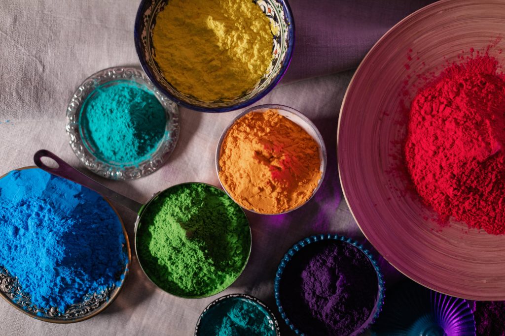 Vibrant Holi festival wallpaper with colorful gulal powder bowls in red yellow blue green purple