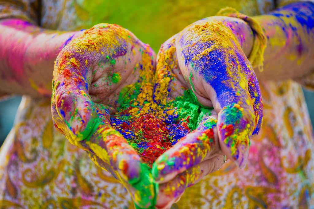 Hands holding vibrant Holi colored powder gulal celebrating the festival of colors joyfully Wallpaper