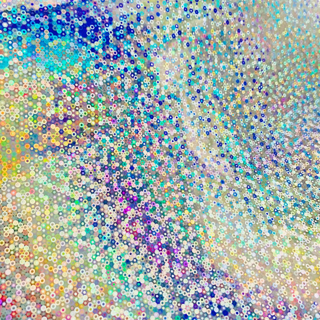 Macro view of vibrant holographic wallpaper with iridescent glittery dots in prismatic colors