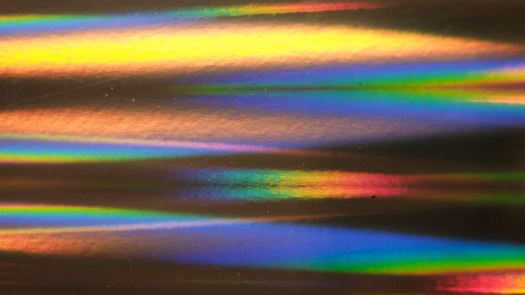 Bright holographic wallpaper with vibrant horizontal rainbow bands of glowing yellow blue orange light