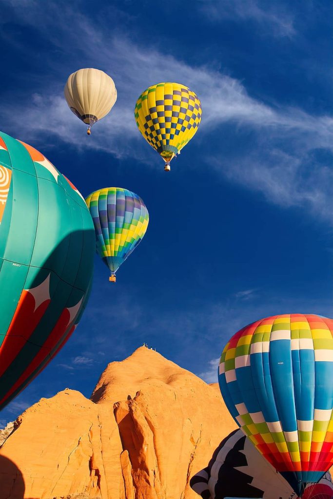 Vibrant hot air balloons over golden desert rocks under clear blue sky wallpaper background