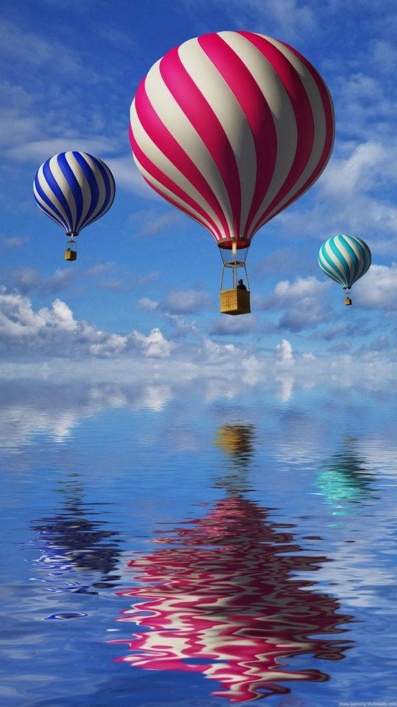 Three vibrant striped hot air balloons soaring above calm reflective water under clear sky wallpaper