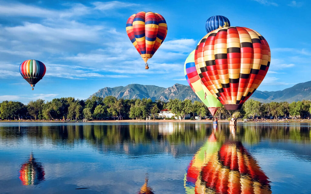 Vibrant Hot Air Balloons Over Calm Lake | Serene Landscape Background Wallpaper
