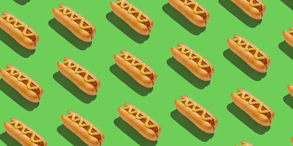 Vibrant hot dog wallpaper with diagonal mustard-topped hot dogs on bright green background