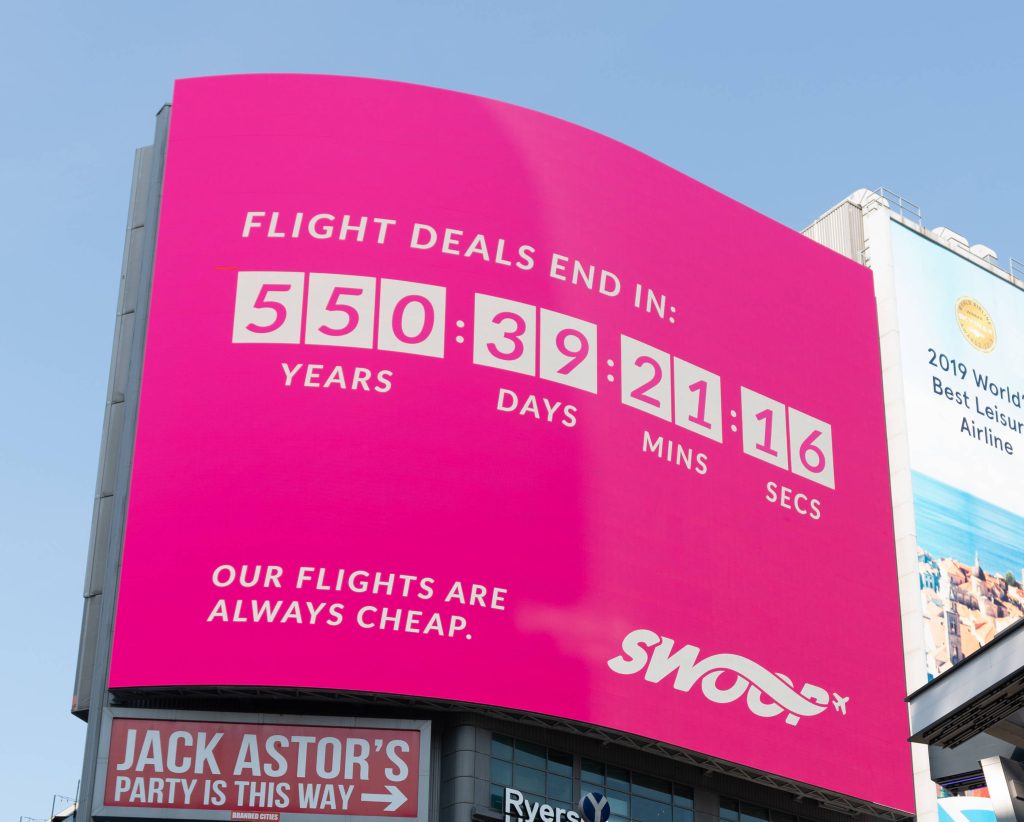 Vibrant hot pink Swoop Airlines billboard with countdown and cheap flights slogan in cityscape Wallpaper