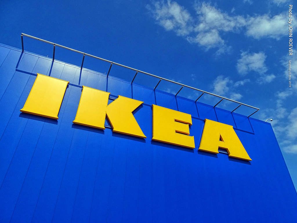 Low angle vibrant IKEA yellow signage on blue building with bright cloudy sky backdrop wallpaper