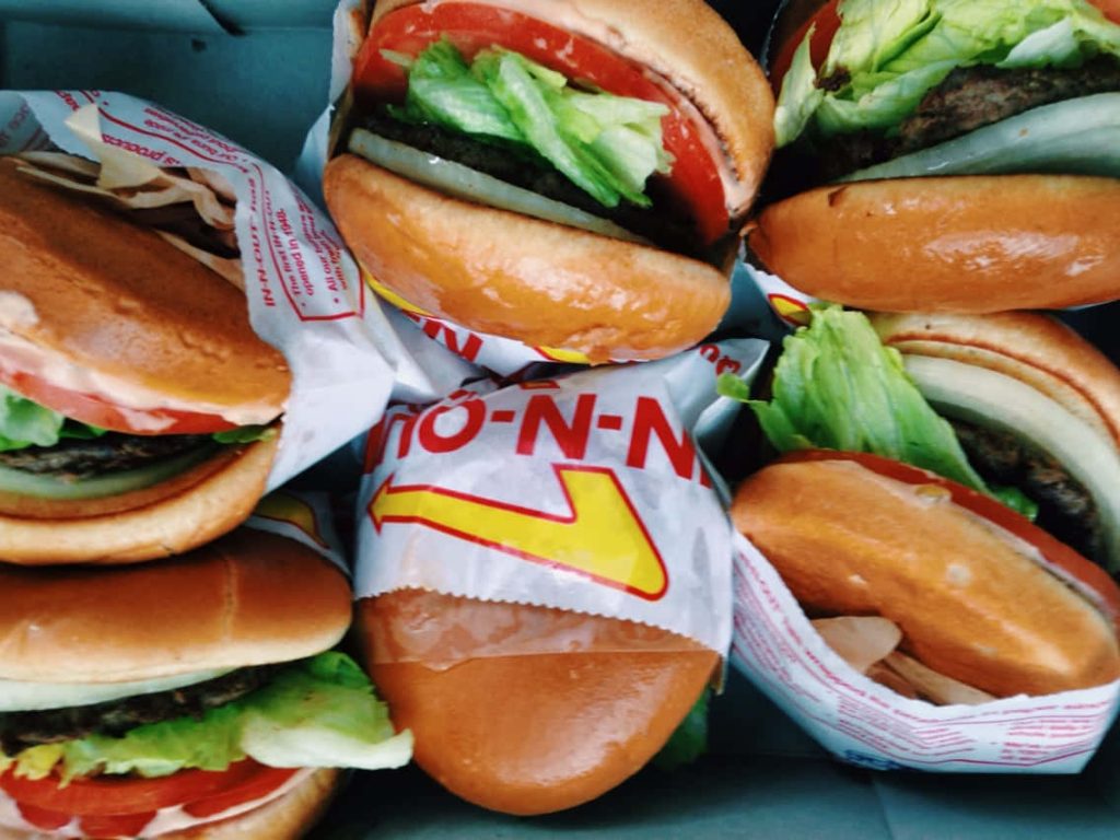 Overhead shot of multiple fresh In-N-Out Burgers with toasted buns and signature packaging Wallpaper