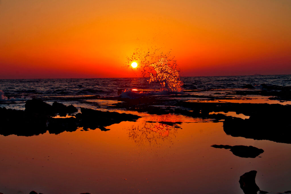 Sunset over Indian beach with vibrant sky and dramatic water splash in calm ocean background Wallpaper