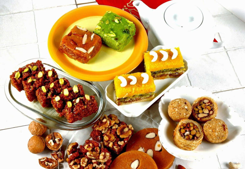 Vibrant Indian Sweets Wallpaper: Desserts & Teapot on White Background