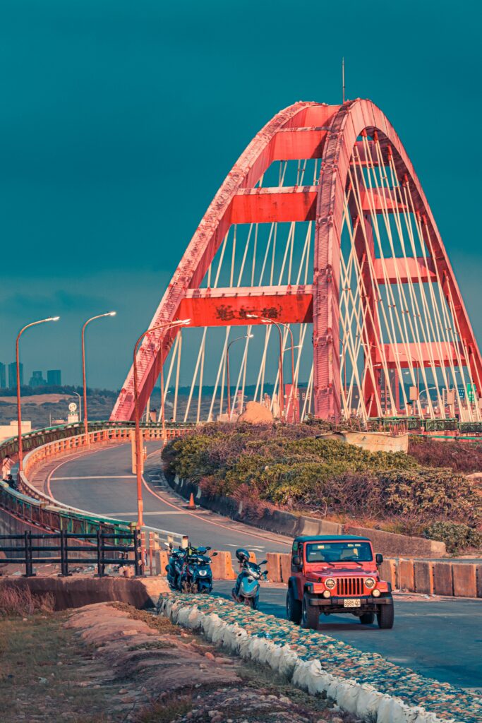 Vibrant Wallpaper: Red Jeep & Bridge on a Scenic Blue Sky Road