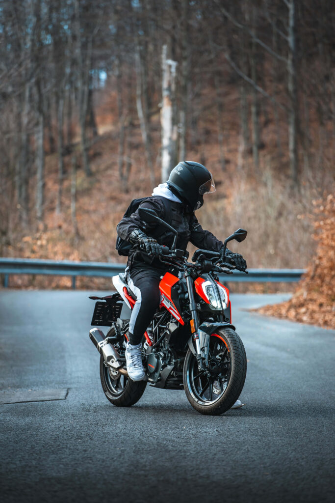 Vibrant KTM Duke 390 Wallpaper: Man Riding Through Serene Forest