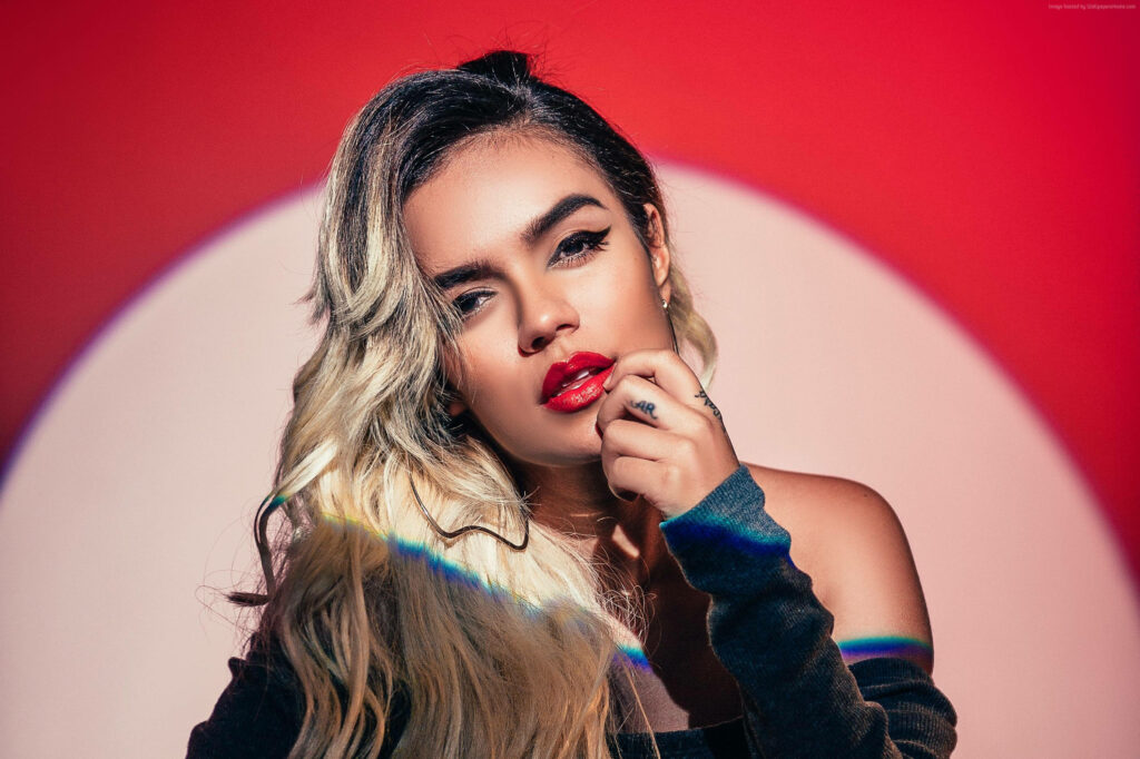 Vibrant Karol G Wallpaper: Bold Makeup & Dramatic Red Background