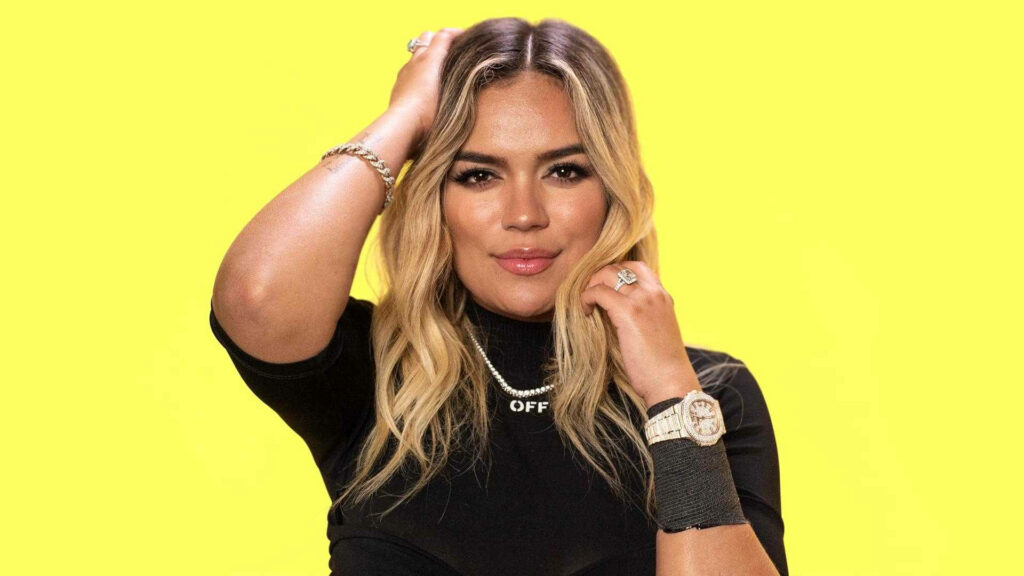 Karol G Wallpaper: Confident Pose on Bright Yellow Background