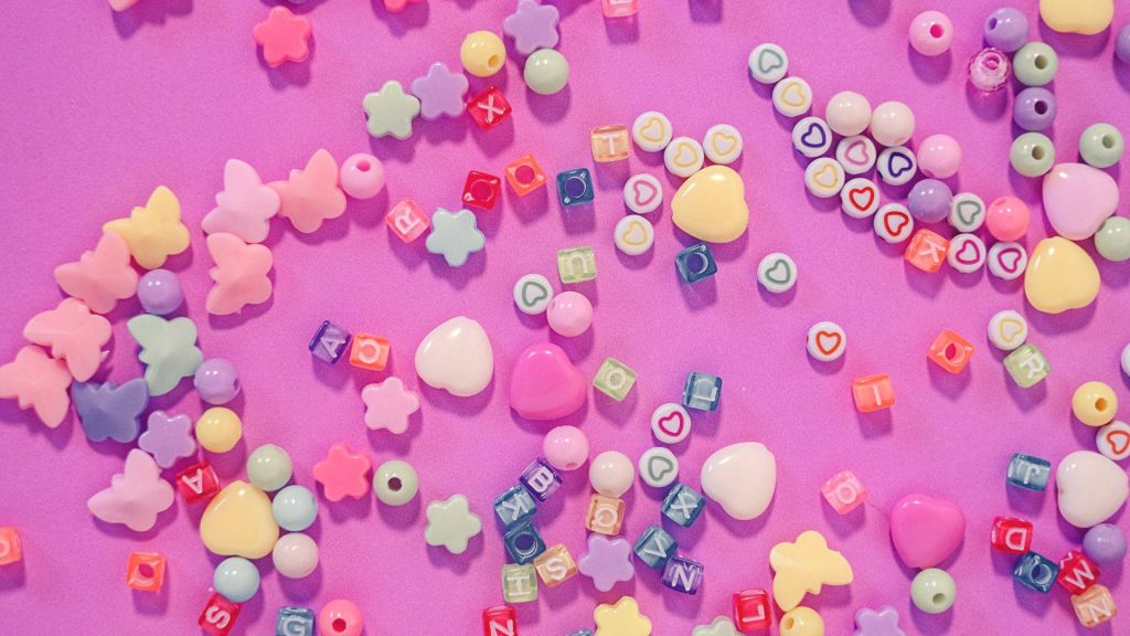 Kidcore wallpaper with colorful craft beads letters hearts stars butterflies on purple background