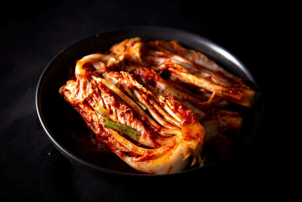 Vibrant Kimchi on Black Plate: Striking Red Hues Wallpaper Background