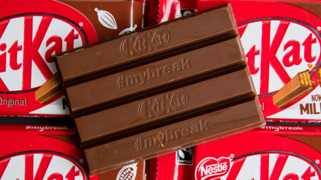 Close-up Kit Kat bar with mybreak hashtag on chocolate against colorful wrappers background Wallpaper