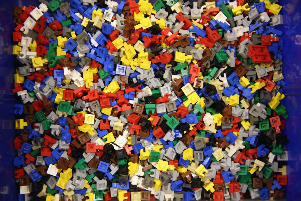 Colorful Lego pieces mixed in various shapes and sizes scattered in a box background Wallpaper