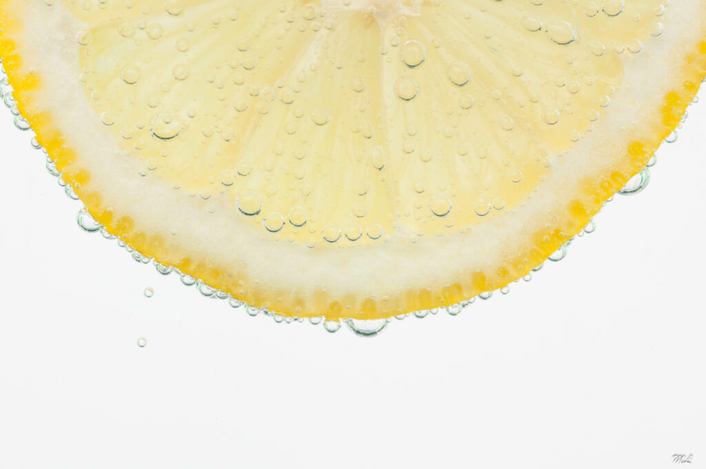 Vibrant Lemon Slice Macro with Bubbles on White Wallpaper Background