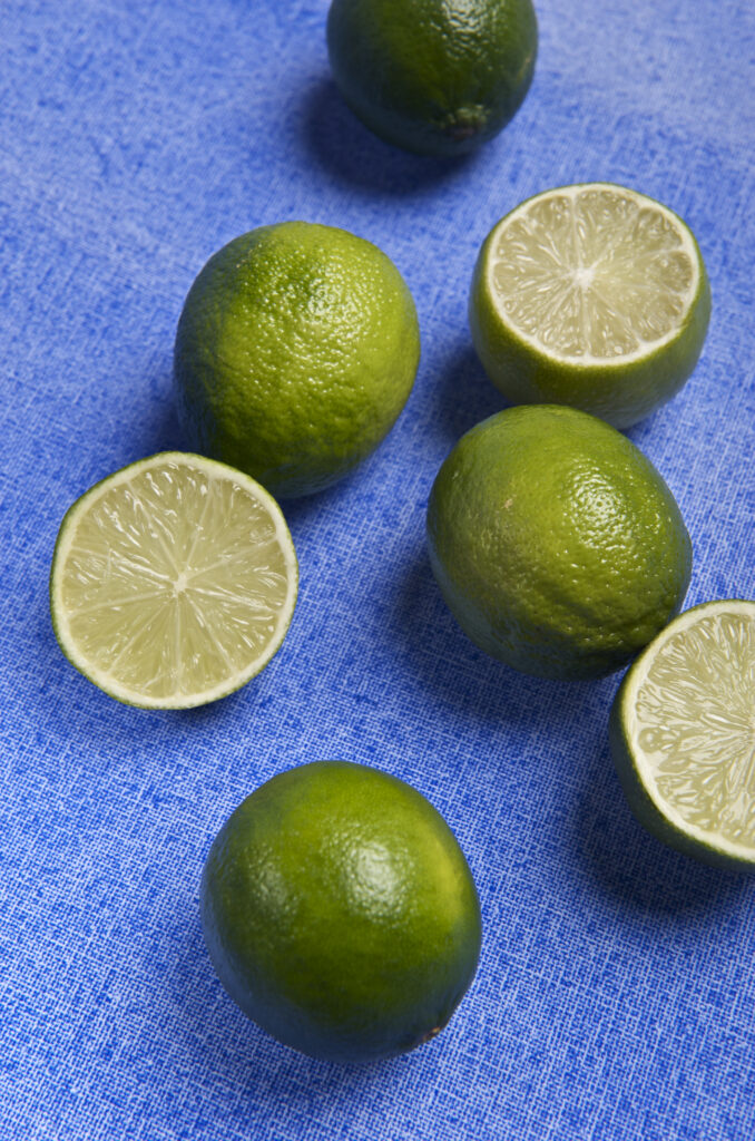 Vibrant Lime Wallpaper: Fresh Green Fruit on Textured Blue Fabric