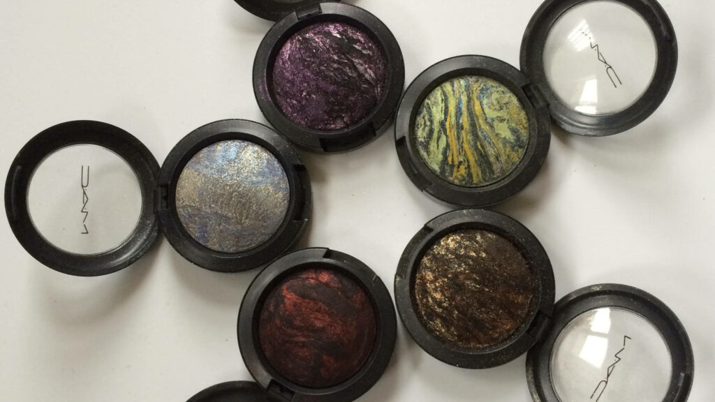 Close-up of MAC Cosmetics marbled eyeshadows in purple silver yellow green red and bronze shades Wallpaper