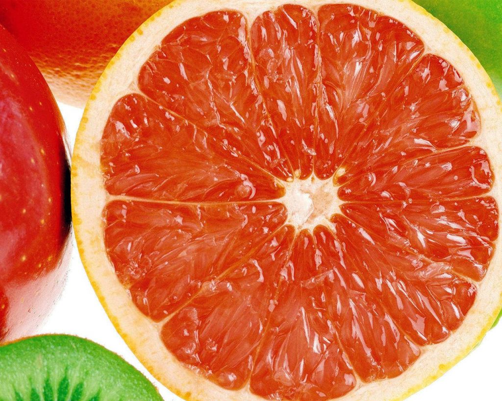 Macro shot of juicy red grapefruit with fresh kiwi and apple for vibrant healthy wallpaper background