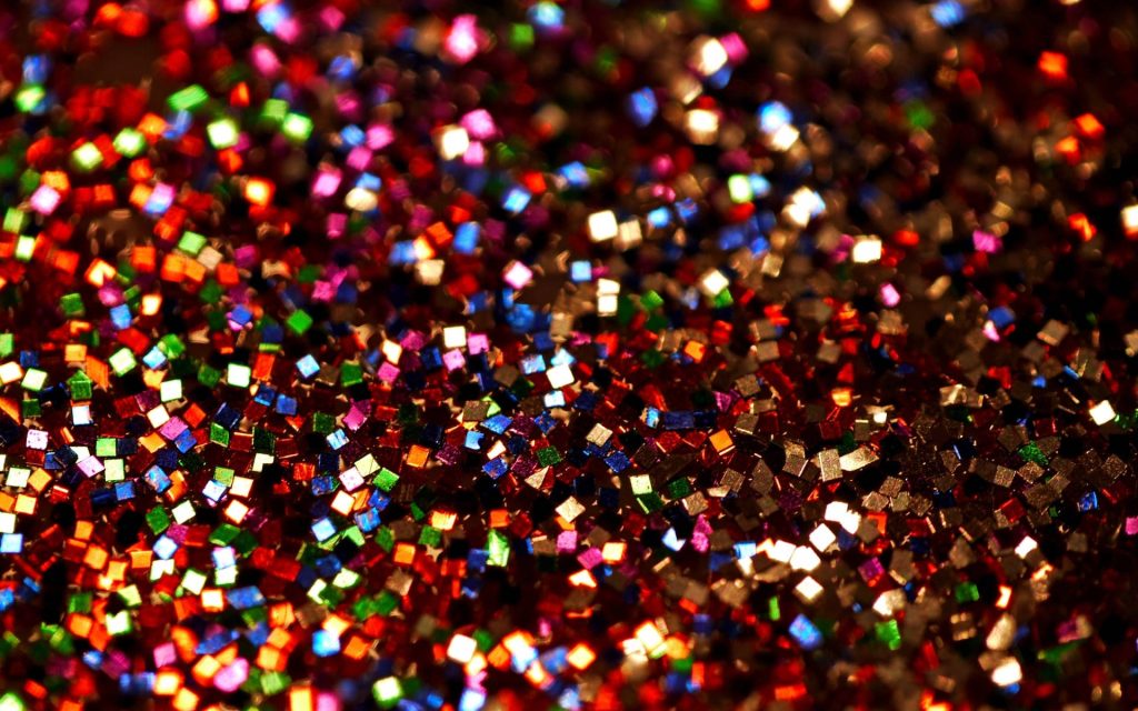 Vibrant macro wallpaper of dense rainbow square glitter creating a sparkling bokeh effect background