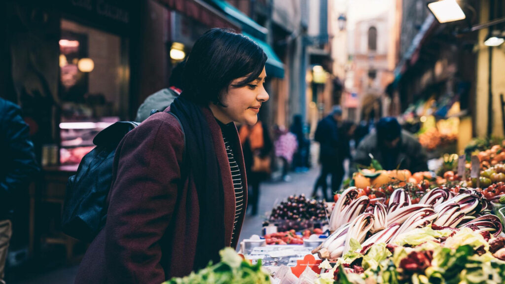 Vibrant Market Exploration: Girl Amid Fresh Produce Wallpaper