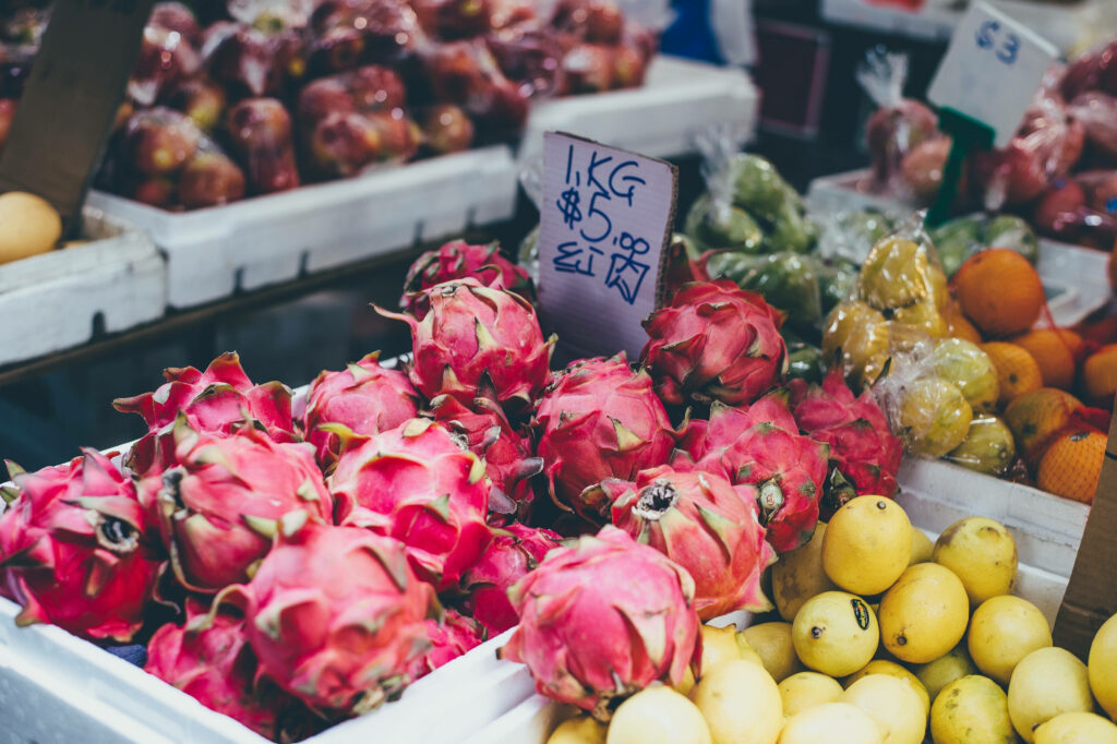 Vibrant Market Scene: Fresh Dragonfruit, Pears & Oranges Wallpaper