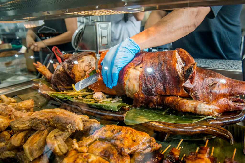 Vibrant Market Scene: Freshly Roasted Lechon & Filipino Delicacies Wallpaper