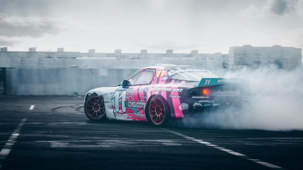 Foggy Drift: Mazda Rx-7 Spins and Slides in Vibrant Colored Car Wrap amidst Dense Mist Wallpaper
